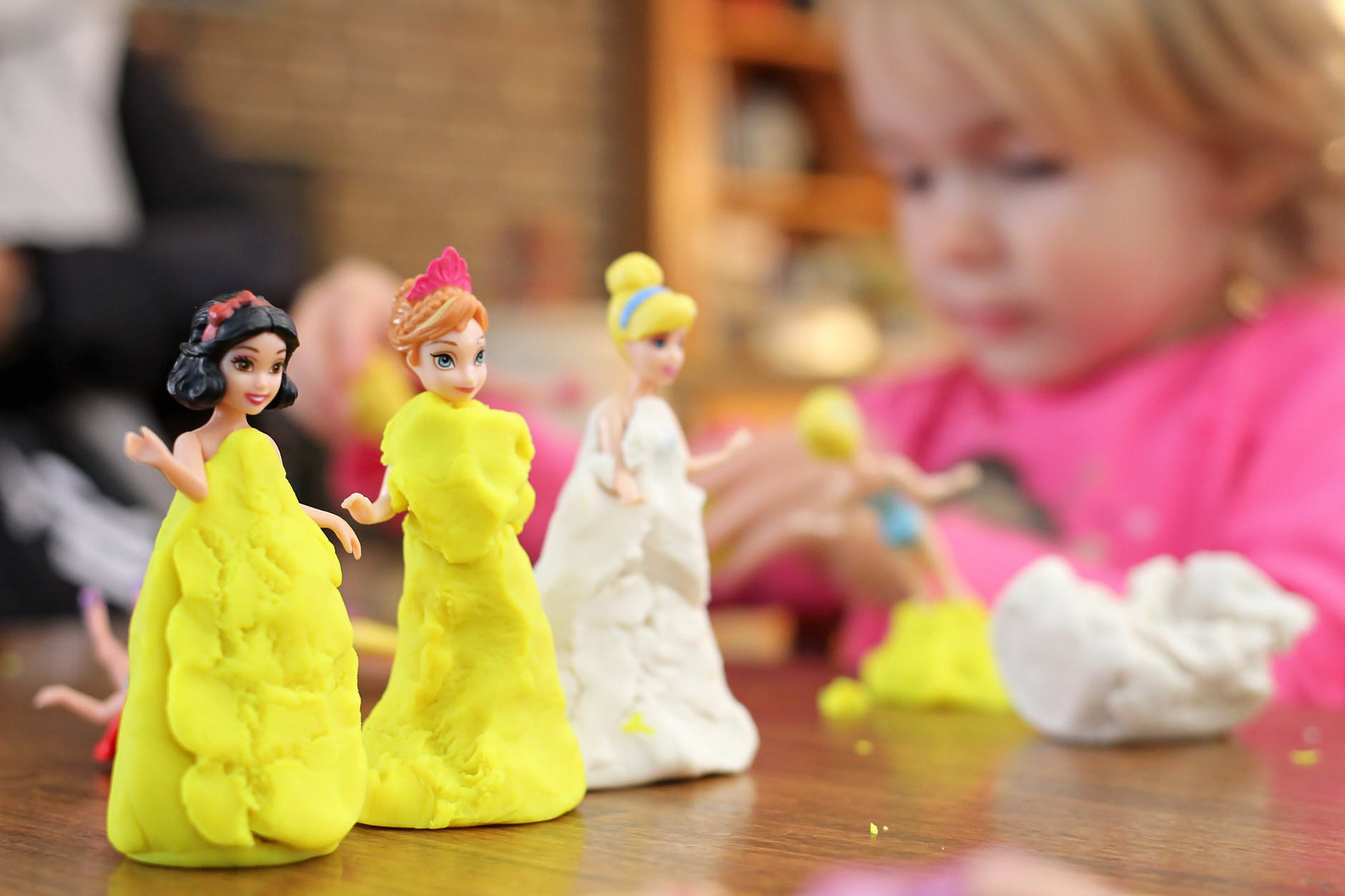 selective focus photography of three disney princesses figurines on brown surface
